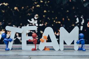 Kleine, bunte Figuren halten die Buchstaben für das Wort "Team".